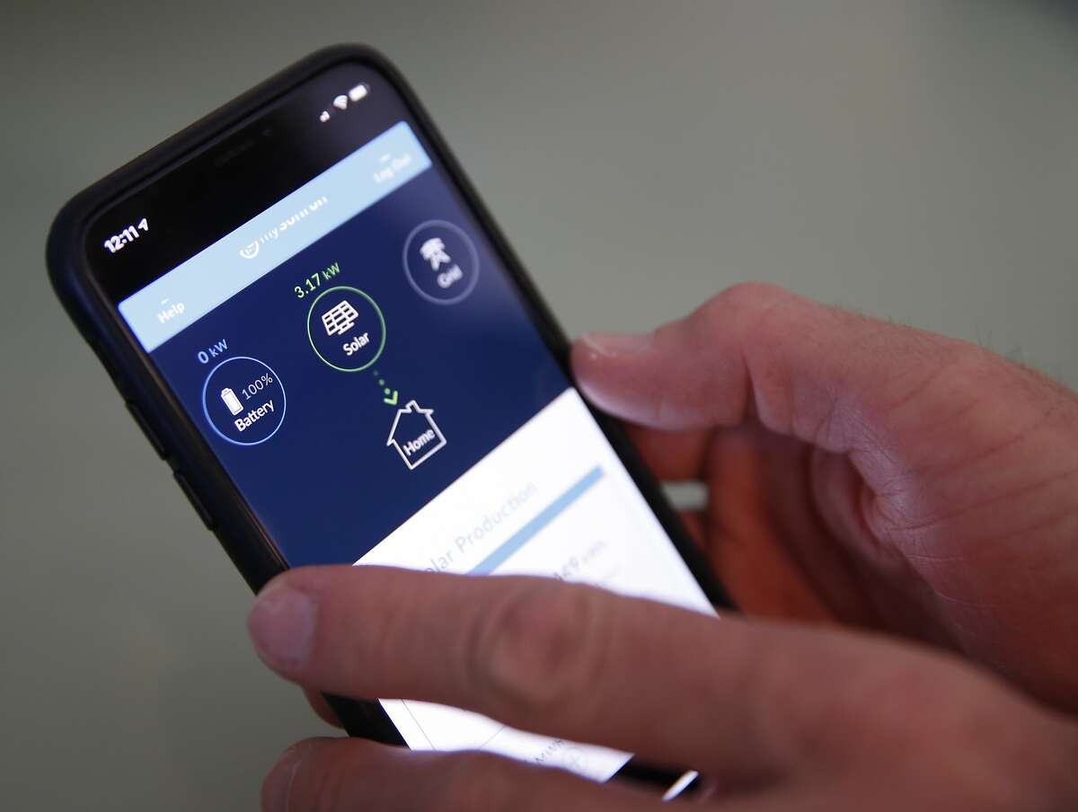 Derek Krause uses an app to monitor the solar energy and backup battery system installed at his home in Oakland, Calif. on Tuesday, Oct. 22, 2019.