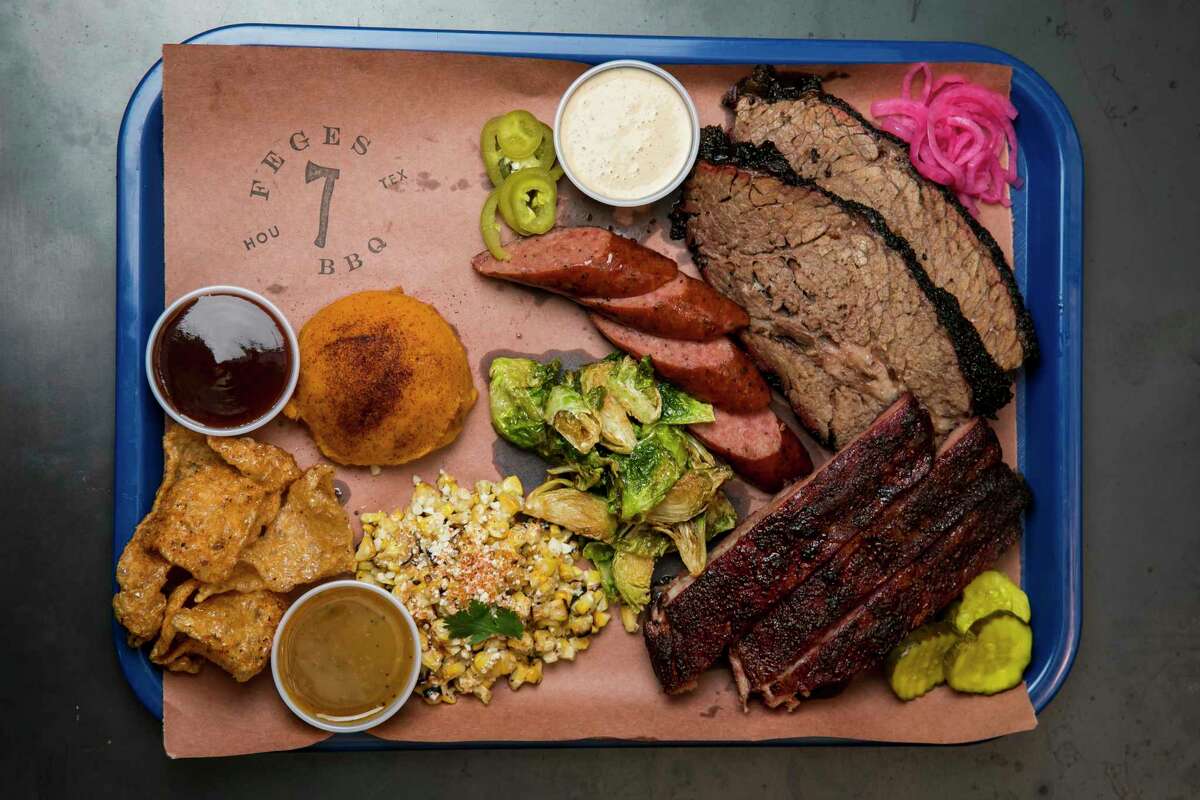A barbecue platter featuring the Texas Trinity — brisket, pork ribs and sausage — with sides at Feges BBQ