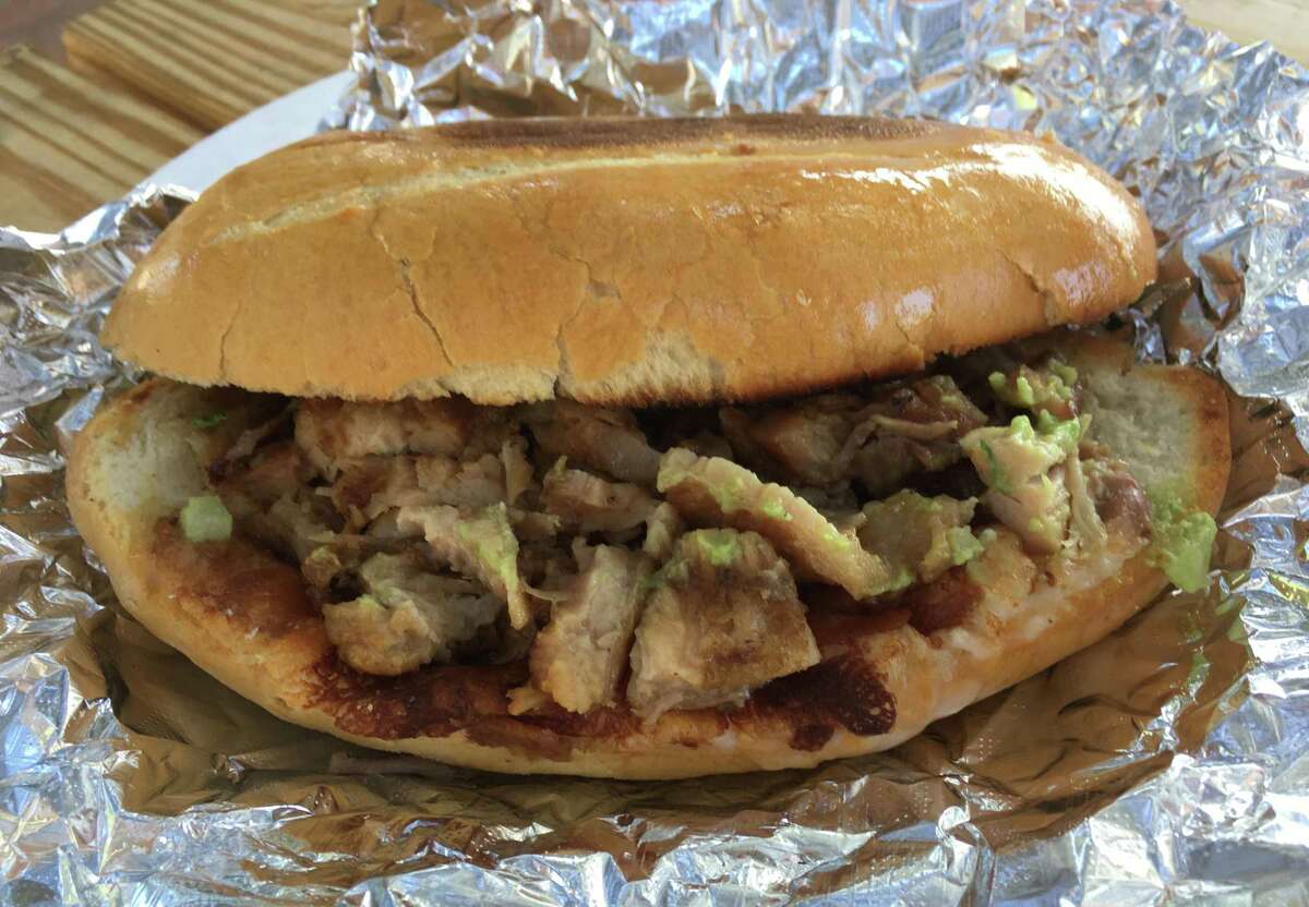 A pork belly torta served “moreliana” style with guacamole, beans and cheese at Carnitas Don Raúl.