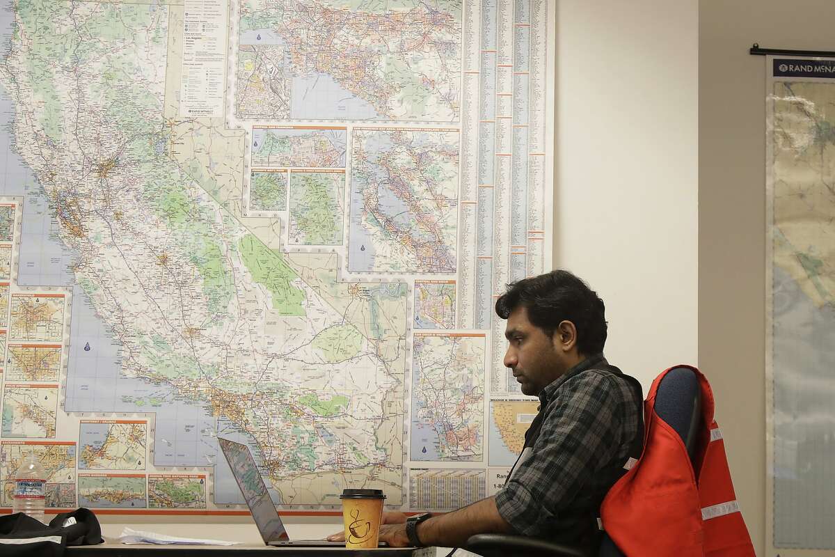 FILE - In this Oct. 10, 2019, file photo, Senior program analyst Siva Jasti works next to a map of California in the Pacific Gas & Electric (PG&E) Emergency Operations Center in San Francisco. The California Senate will investigate a California utility's process for cutting off power to more than 2 million people to prevent wildfires. In a memo to the Senate Democratic Caucus on Thursday, Oct. 17, 2019, Senate President Pro Tempore Toni Atkins asked the Senate Energy, Utilities, and Communications Committee to "begin investigating and reviewing options to address the serious deficiencies" with PG&E's current process of shutting off power to prevent wildfires. (AP Photo/Jeff Chiu, File)