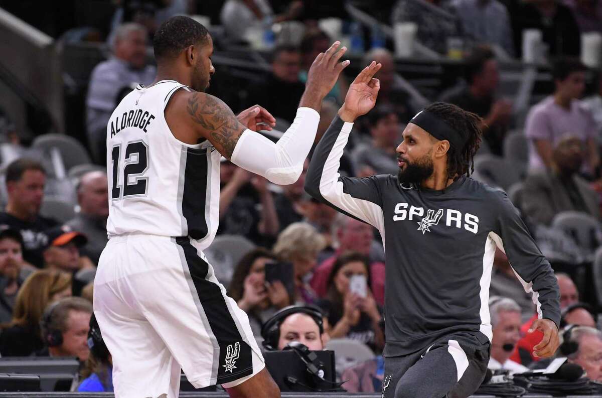 San Antonio Spurs forward LaMarcus Aldridge is greeted by teammate Patty Mills before the tipoff of the team's season opener against the New York Knicks in the AT&T Center on Wednesday, Oct. 23, 2019.