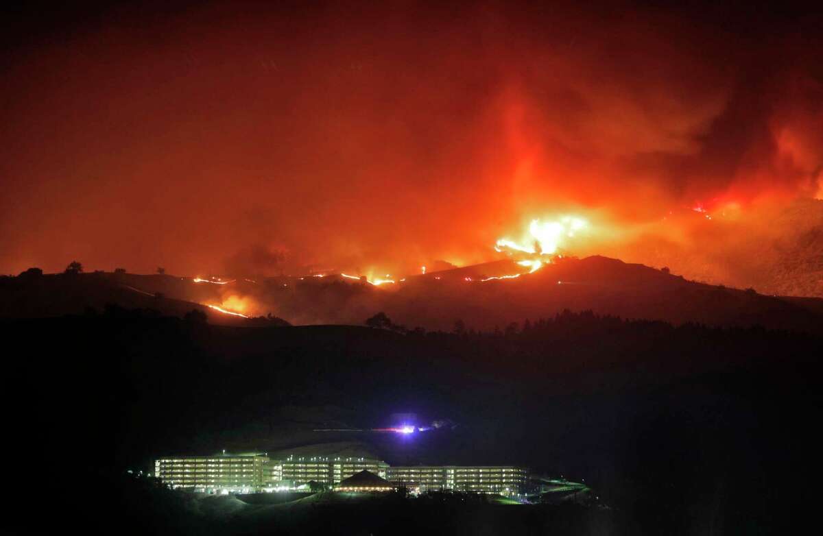 The River Rock Casino sits below a ridge line on fire as the Kincade Fire burns outside Geyserville, Calif., on Thursday, October 24, 2019.