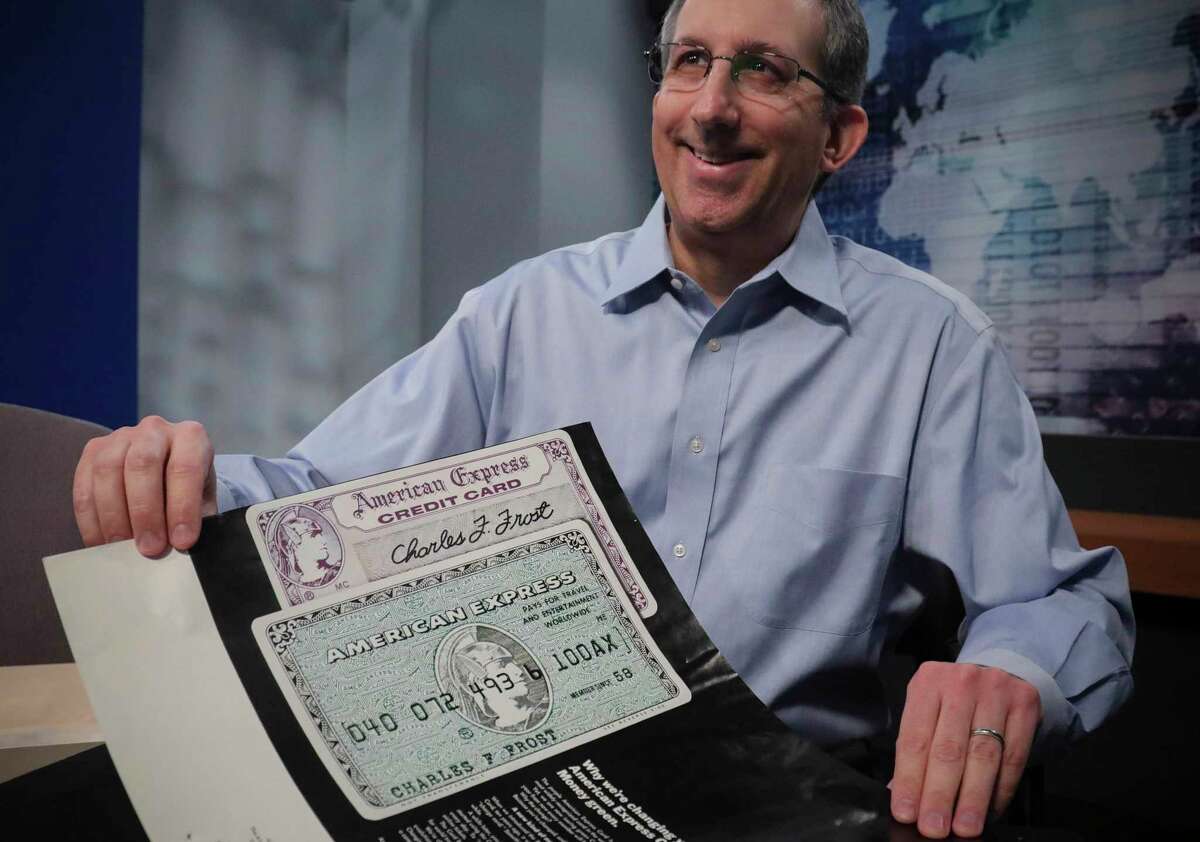 In this Wednesday, Oct. 23, 2019, photo Ira Galtman, American Express director of corporate archives, shows a 1969 ad introducing the American Express "Green Card" and changing its purple color in New York. For 50 years the "Green Card" was everywhere and has been revamped, with a new look and more travel benefits. (AP Photo/Bebeto Matthews)