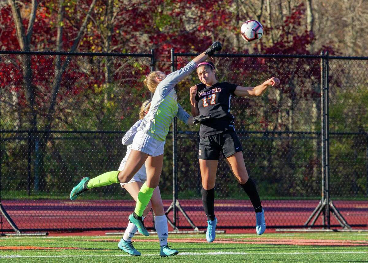 Wilton goalie Erynn Floyd punches the ball away from Ridgefield's Tasha Riek.