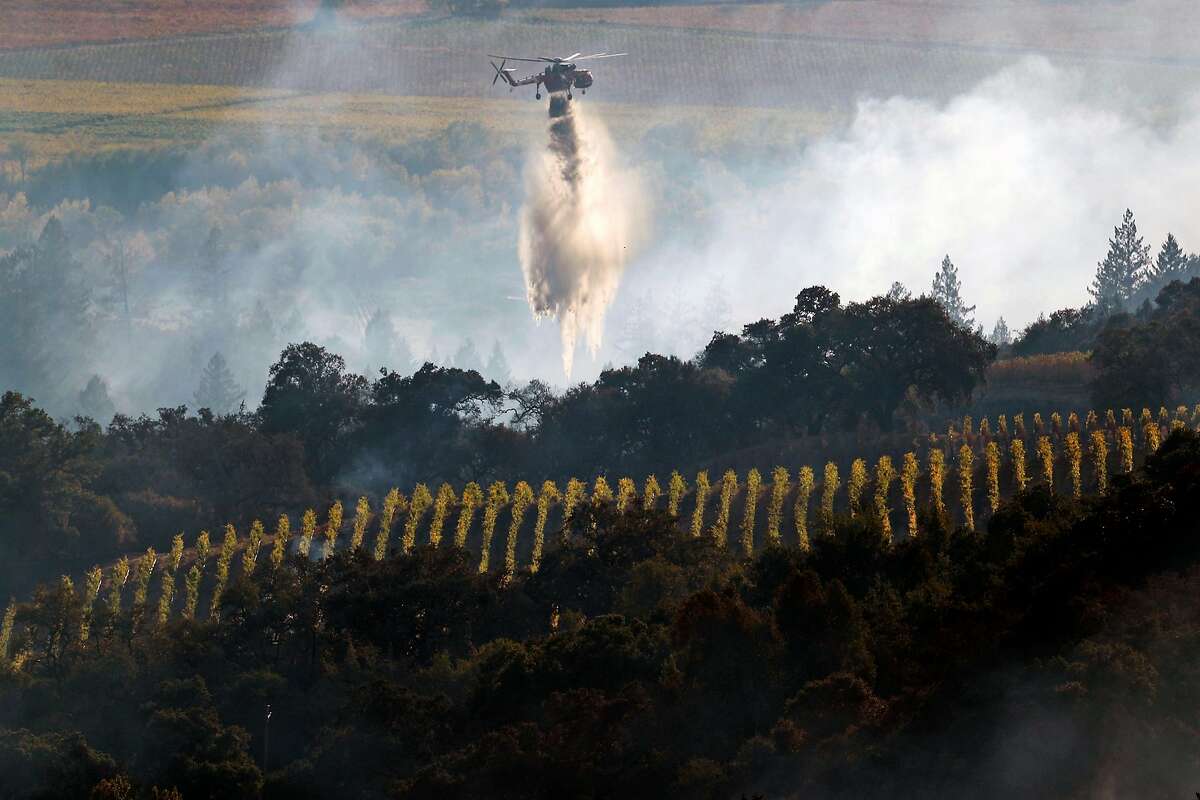A helicopter drops water near a vineyard during Kincaid Fire in Geyserville, Calif., on Thursday, October 24, 2019.