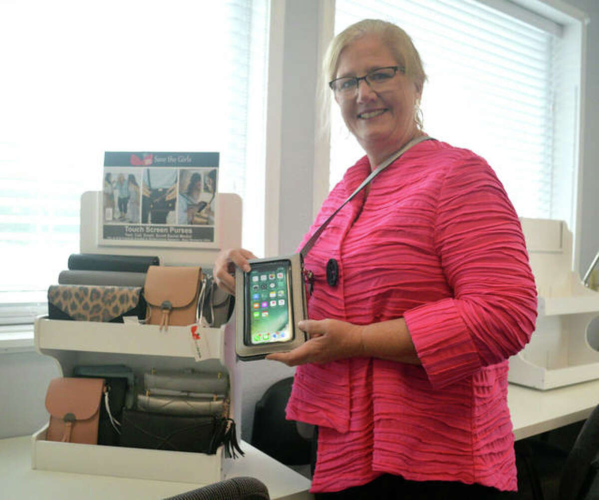 Edwardsville resident Tami Lange, founder and designer of Save the Girls, holds one of the touch screen phones that her company sells at its office and warehouse in Belleville.