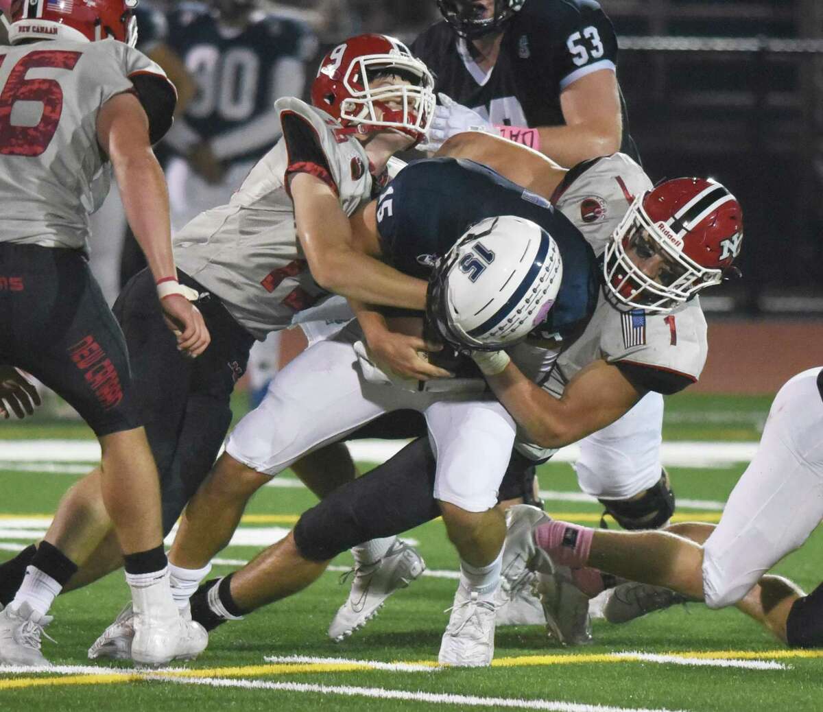 New Canaan's Chris Carratu (1) and Jack Hagan (19) tackle Staples' Jake Thaw (15) during a football game in Westport on Friday, Oct. 25, 2019.