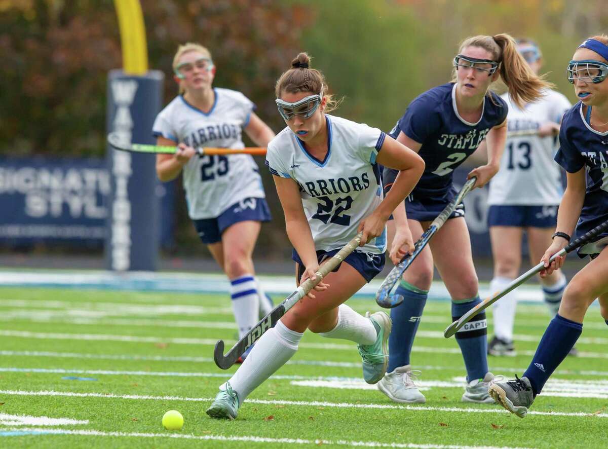 Wilton's Olivia Hahn cuts between Staples' Kyle Kirby (#2) and Laine Ambrose during Friday's field hockey game.