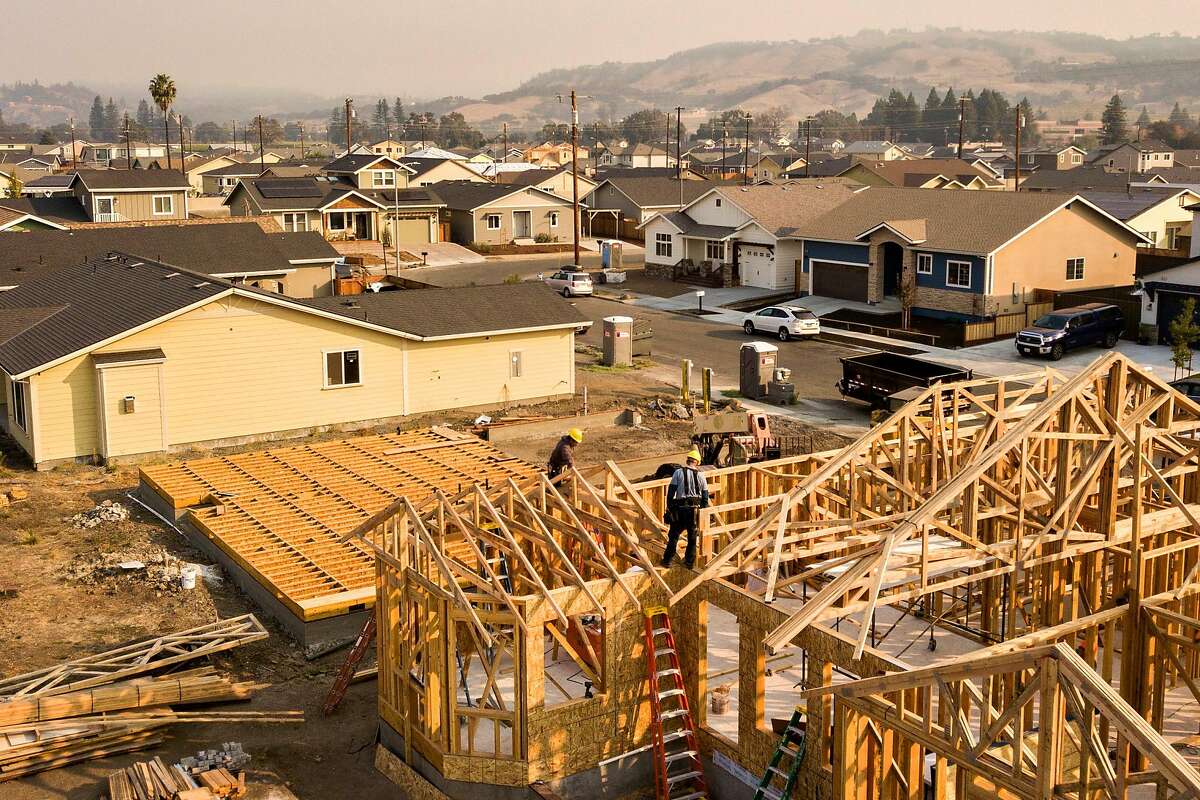 Prestige Home and Remodel Inc. workers build a home in the Coffey Park neighborhood as the Kincade Fire smoke fills the air on Friday, Oct. 25, 2019, Santa Rosa, Calif. The Coffey Park neighborhood continues to rebuild after it was destroyed in the Tubbs Fire of October 2017.