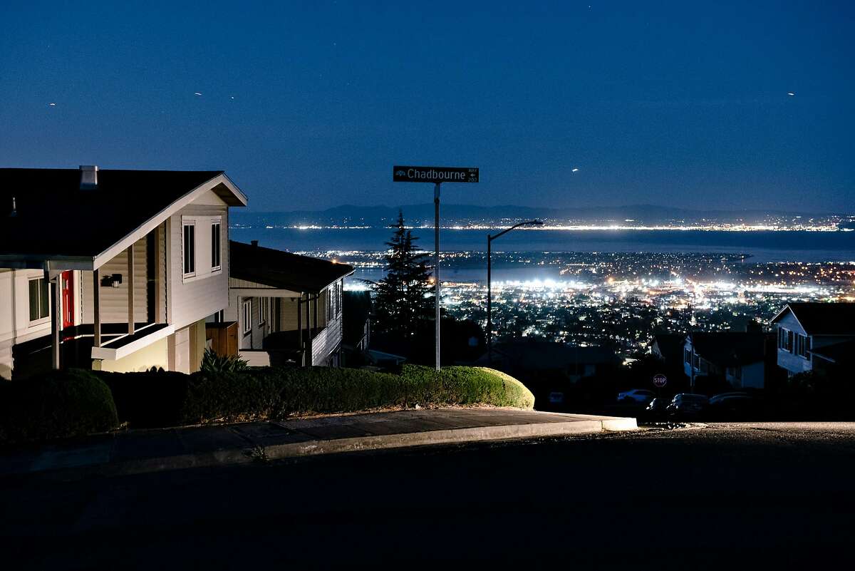 Oakland city lights are seen in the distance behind darkened homes off of Skyline Boulevard in Oakland, California, on Friday, Oct. 10, 2019. PG&E planned power outages affected parts of Oakland and Alameda County as the utility fights to stave off wildfires that can be caused by high winds hitting their power lines.