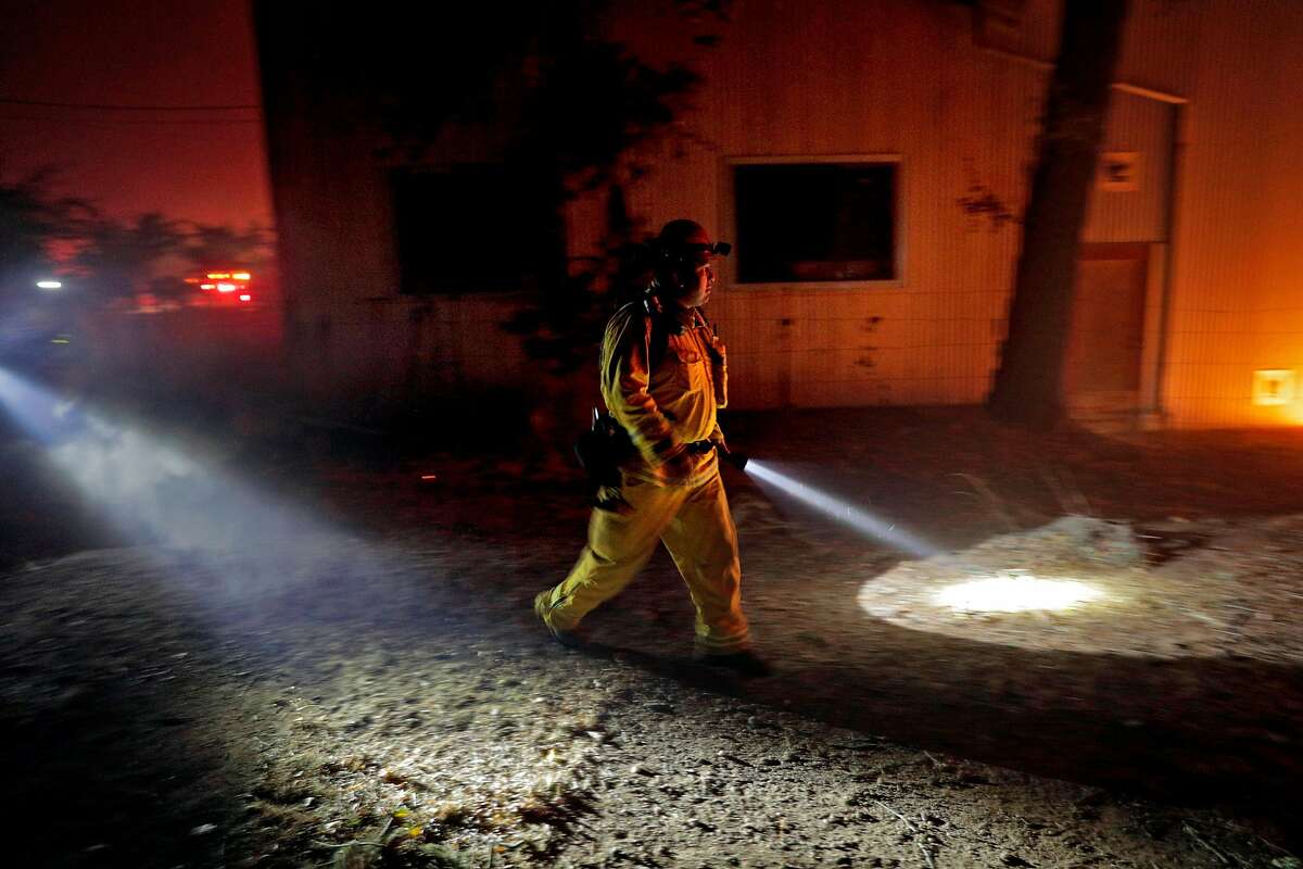 A firefighter exmaines the progress of a fire at the Soda Rock Winery as the Kincade Fire burns outside Healdsburg, Calif., on Sunday, October 27, 2019.