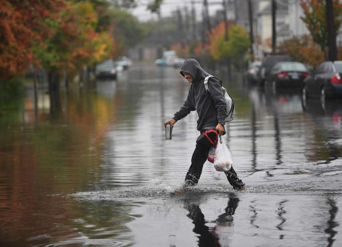 A man crosses a flooded Iranistan Avenue in Bridgeport, Conn. during heavy rains on Thursday, October 24, 2019.
