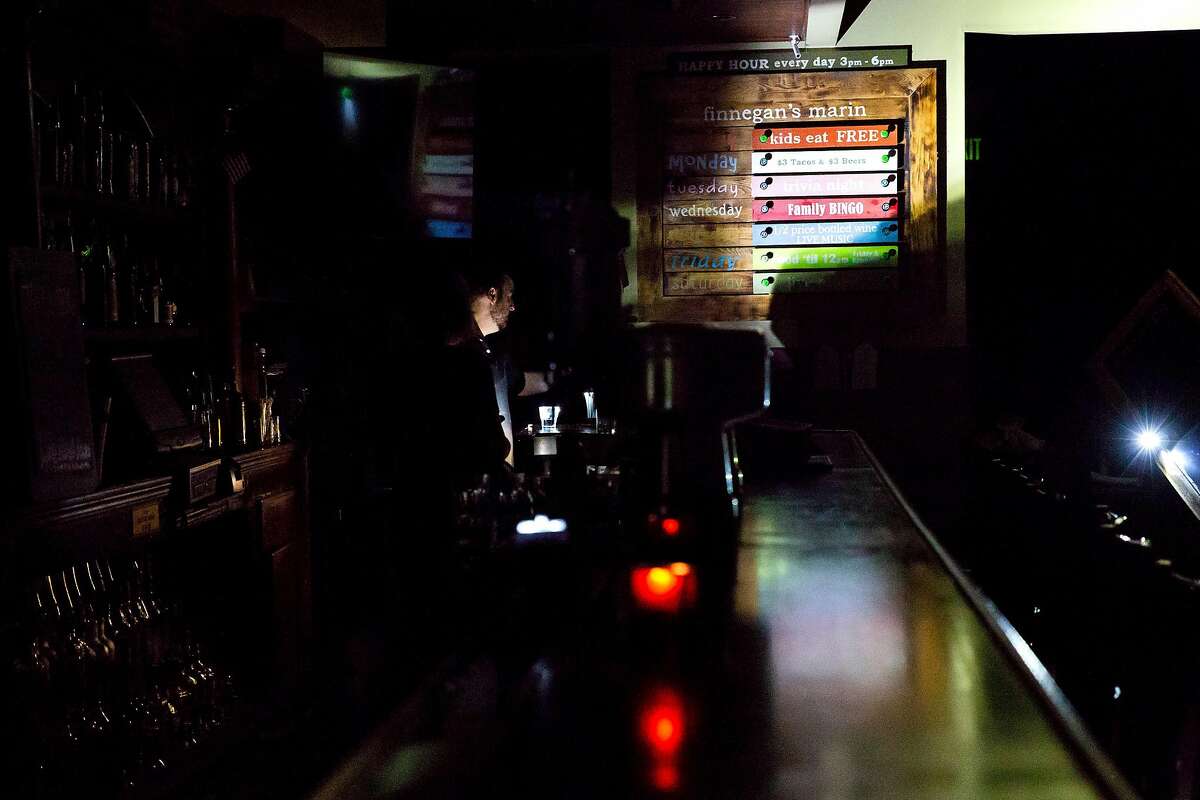 Employees use flashlights to maneuver around the bar at Finnigan's Marin Restaurant and Bar in Novato, Calif. during PG&E's Marin County power shut down on Saturday, Oct. 26, 2019. Residents throughout the North Bay are expected be without power starting Saturday evening as PG&E begins it's second Public Safety Power Shut-Off. PG&E states that over 940,000 residents will be without power through the weekend.