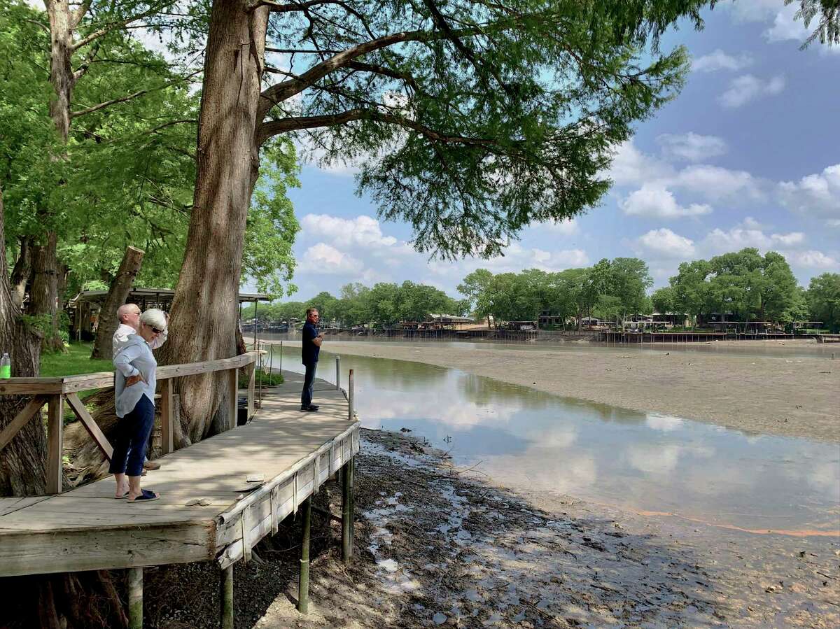 People look at the receding water of Lake Dunlap on May 15, the day after a spill gate collapsed, draining much of the water.