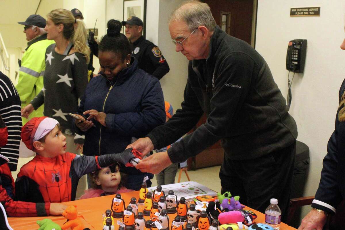 Joe Nixon, of Westport PAL, shows young trick-or-treaters some of the goodies offered at a table in town hall for the annual Halloween parade. Taken Oct. 29, 2019 in Westport, Conn.