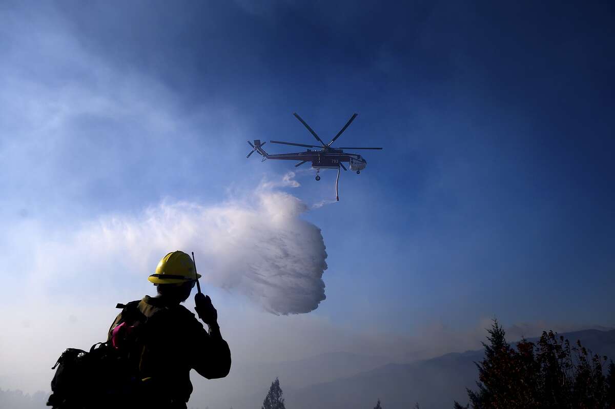 A helicopter drops water while battling the Kincade Fire near Healdsburg, Calif., on Tuesday, Oct. 29, 2019. Millions of people have been without power for days as fire crews race to contain two major wind-whipped blazes that have destroyed dozens of homes at both ends of the state: in Sonoma County wine country and in the hills of Los Angeles. (AP Photo/Noah Berger)
