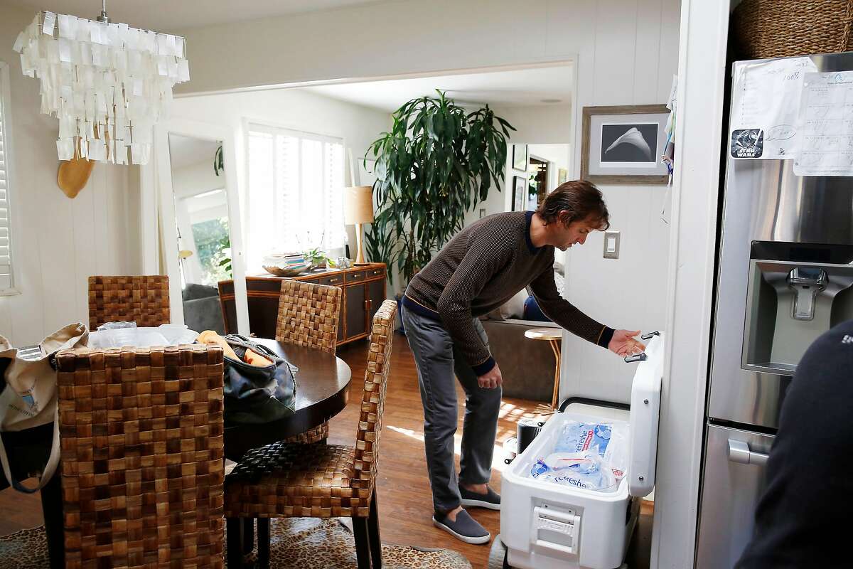John Kuch opens a cooler where a lot of the family’s food is being stored on ice while they have not had electricity on Wednesday, October 30, 2019 in Mill Valley, Calif.