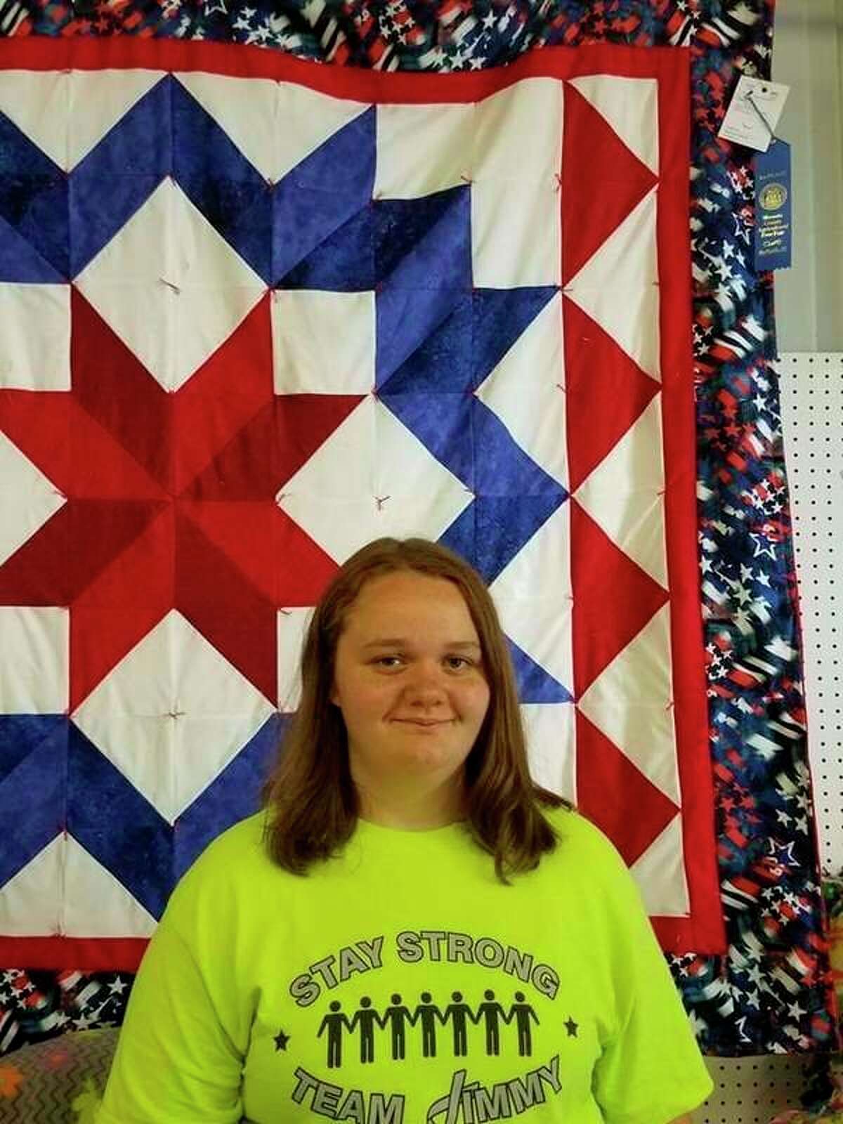 Hailee Young stands in front of one of her ribbon-winning quilts. Her final quilt will be presented at CCA's Veterans Day Tribute on Monday, Nov. 11. (Courtesy photo)