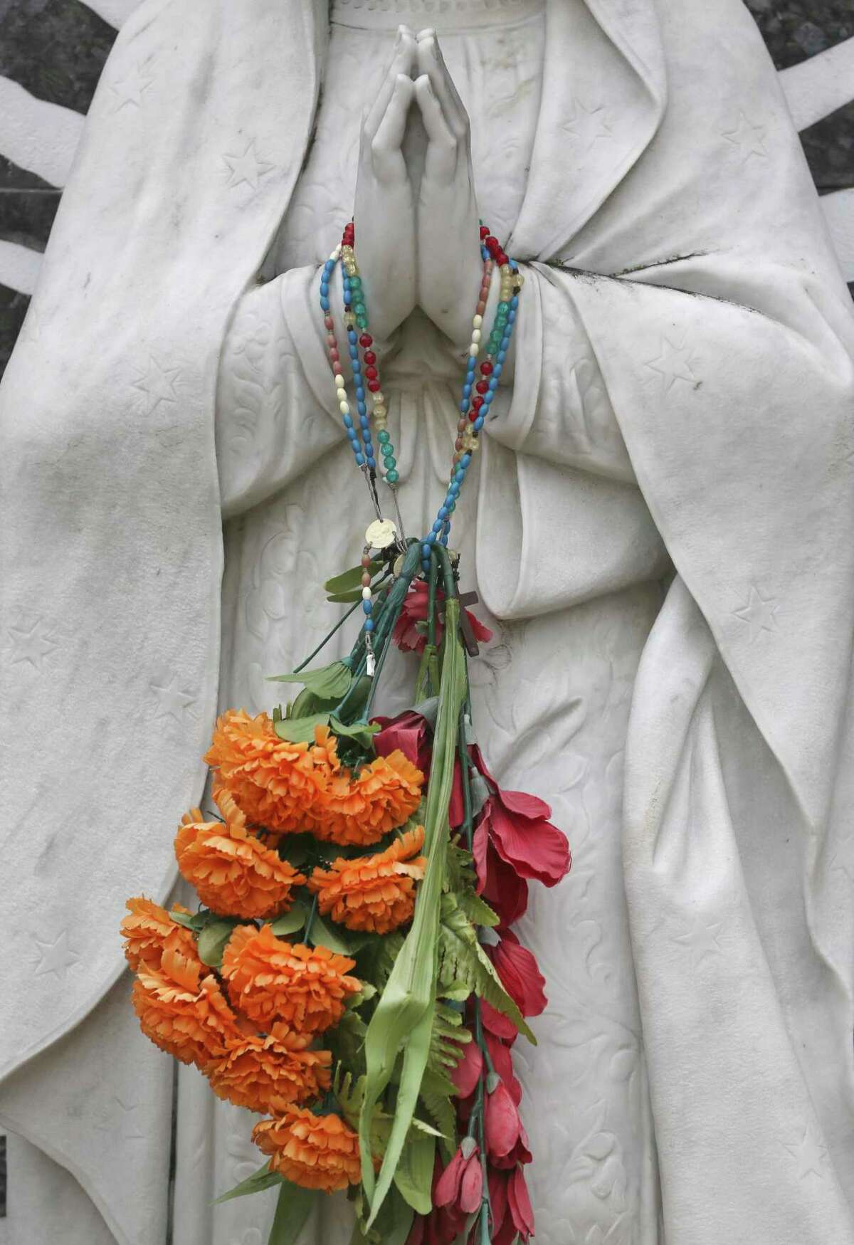 Flowers hang from a Virgin de Guadalupe statue in on All Souls Day.