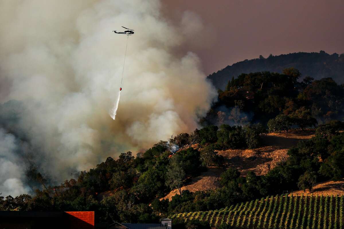 A plane drops water over hill where firefighters worked to contain the Kincade Fire in Geyserville, California, on Thursday, Oct. 24, 2019.