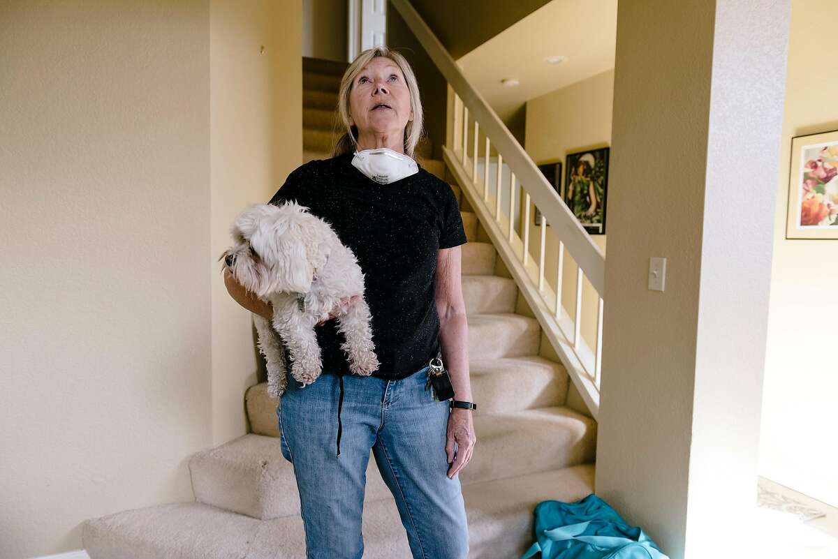 Mary Ann Bainbridge-Krause and her dog Jordie look around while unloading luggage as they returns to her home after evacuating the Kincade Fire in Windsor, California, on Wednesday, Oct. 30, 2019.