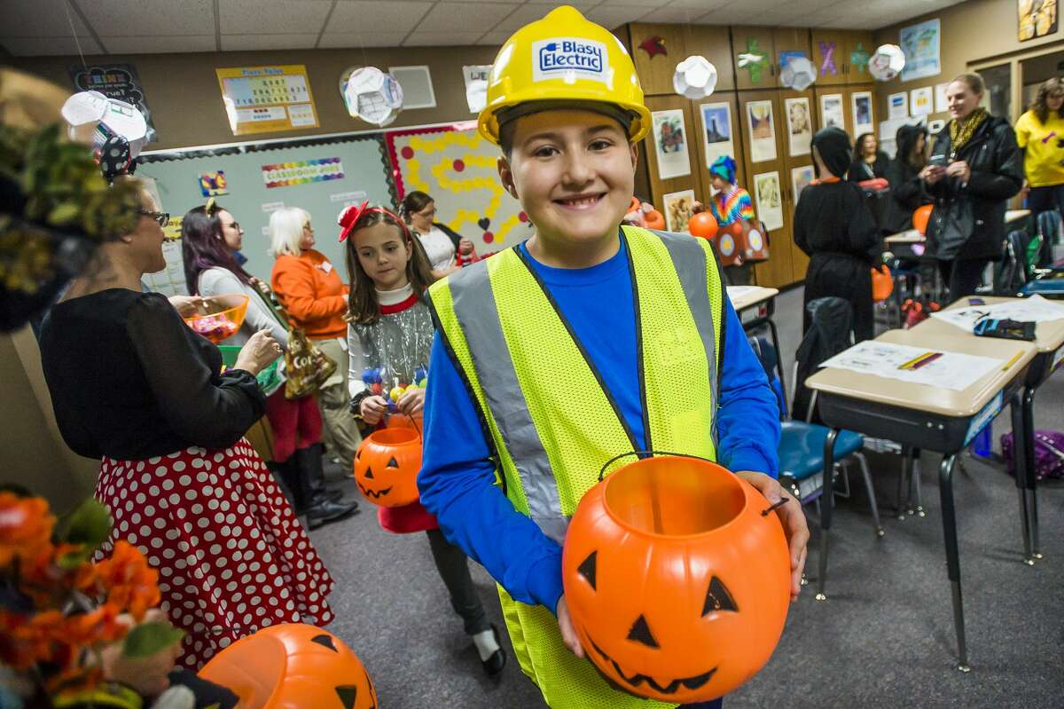 Representatives of businesses in downtown Midland pass out Halloween candy at St. Brigid Catholic School Thursday, Oct. 31, 2019. Each year, St. Brigid students go trick-or-treating through downtown in their costumes, but a steady rain prevented the outdoor parade this year. (Katy Kildee/kkildee@mdn.net)
