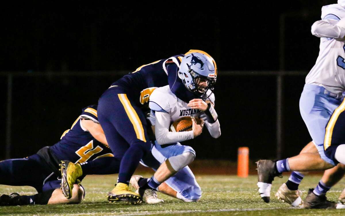 Meridian quarterback Cameron Metzger is sacked by the Ithaca defense Nov. 1, 2019 at Alma College. (Cody Scanlan/for the Daily News)