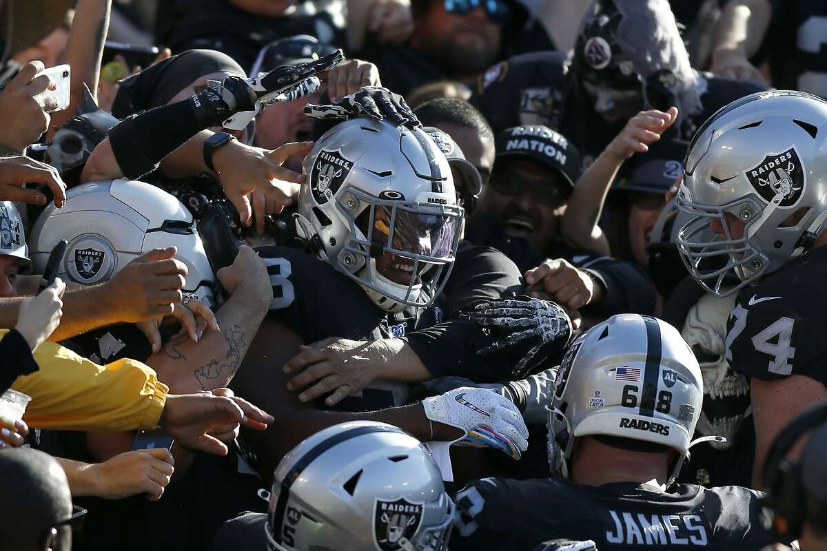 Oakland Raiders running back Josh Jacobs, center, celebrates with teammates and fans after scoring against the Detroit Lions during the first half of an NFL football game in Oakland, Calif., Sunday, Nov. 3, 2019. (AP Photo/D. Ross Cameron)