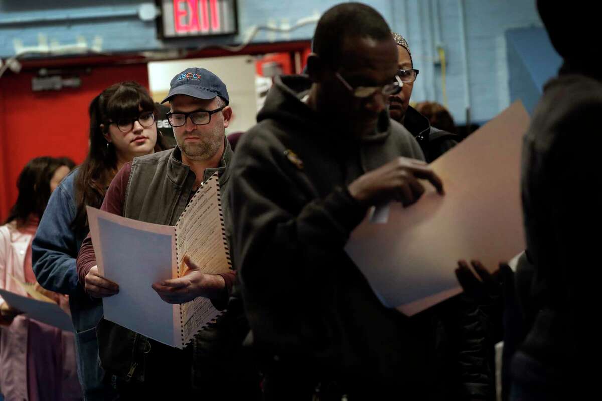 In this Nov. 6, 2018 file photo, voters read their ballot papers as they wait in line to cast their vote at P.S. 161 in Brooklyn borough of New York. A ballot measure will give New York City residents a chance to institute ranked choice voting in primaries and special elections. Under the system now in effect in cities such as San Francisco and Cambridge, Massachusetts as well as the entire state of Maine, voters can rank candidates in order of preference instead of choosing just one.(AP Photo/Wong Maye-E, File)