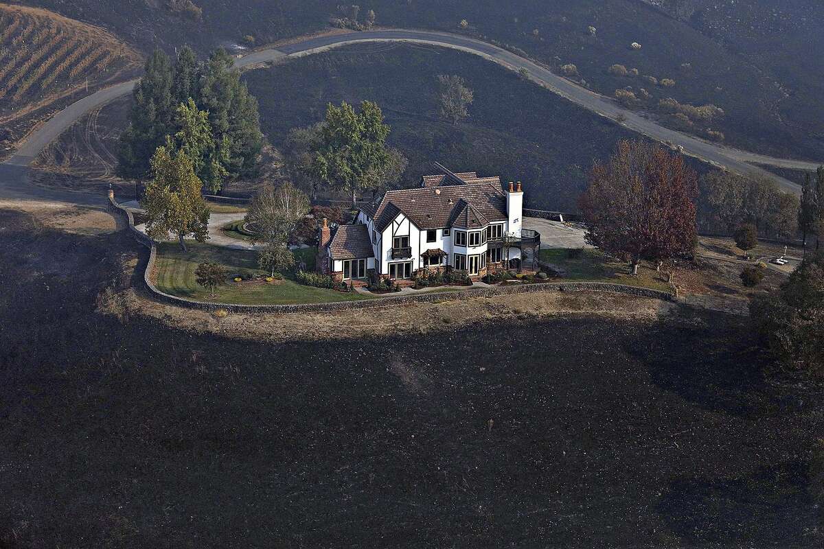 A home between Healdsburg and Windsor, Calif., Oct. 29, 2019, is surrounded by charred ground but was spared from the Kincade Fire flames. (Guy Wathen/San Francisco Chronicle via AP)