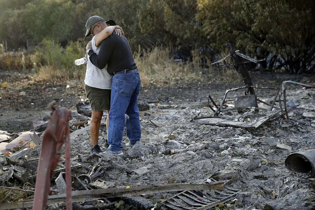 Justo and Bernadette Laos hug while looking through the charred remains of the home they rented that was destroyed by the Kincade Fire near Geyserville, Calif., Oct. 31, 2019. (AP Photo/Charlie Riedel)