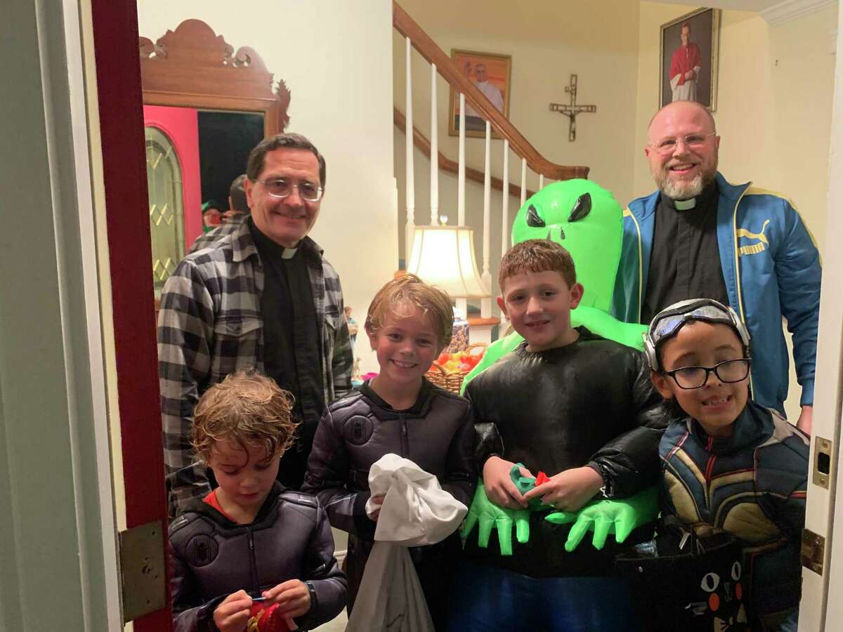 Dash Buffam, Briggs Buffam, Greyden Lumelleau, Zoe Fehring with Monsignor Kevin Royal and Father Sean Kulacz at Saint Mary's rectory on Bryon Avenue on Halloween night.
