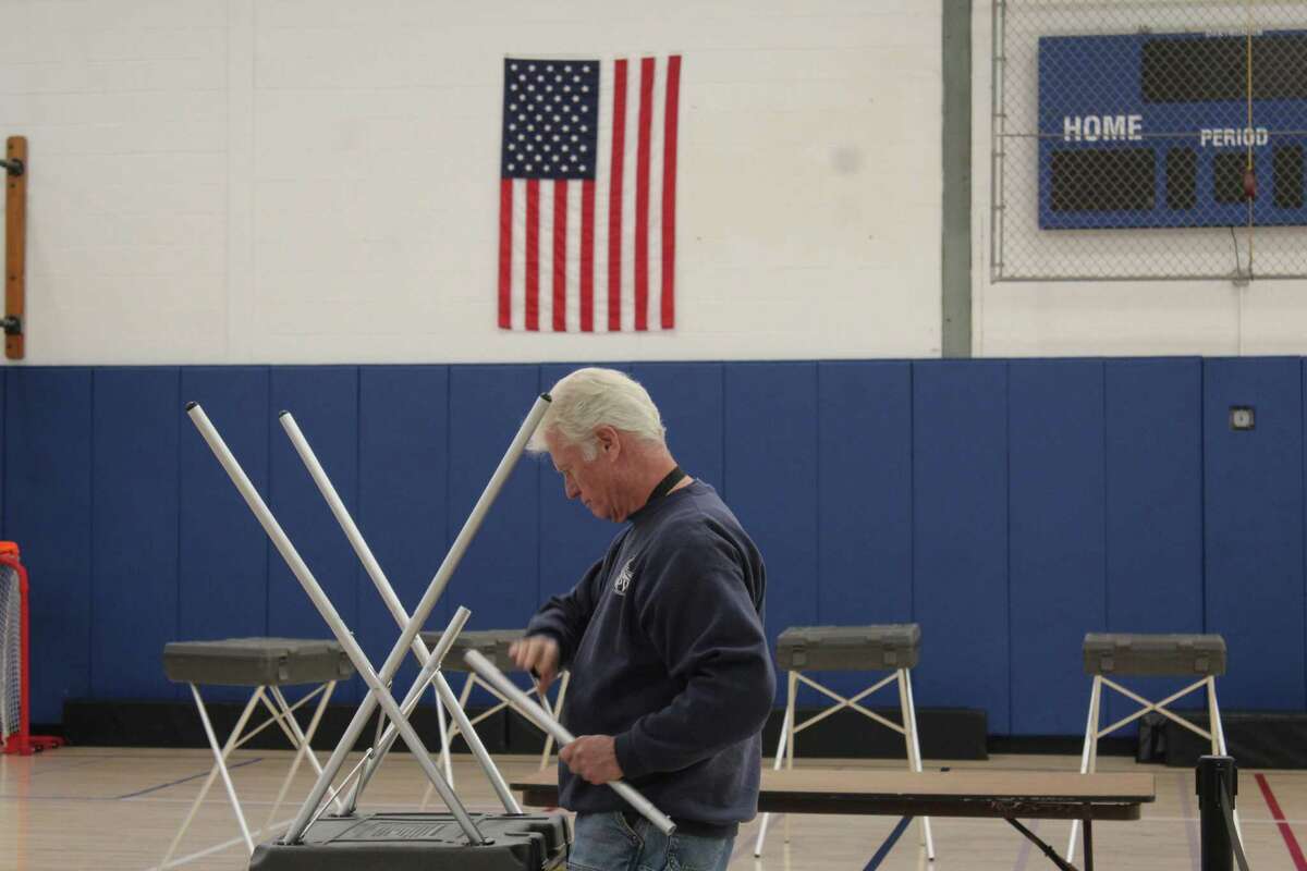 Department of Public Works employee Michael MacDonald sets up a voting booth Monday at Central Middle School, which is the polling place for District 8 in Greenwich.