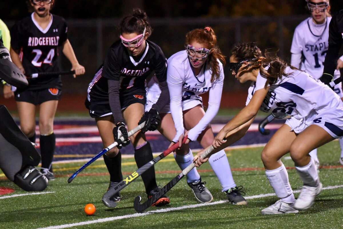 Ridgefield's Olivia DeStefano (11) and Staples' Ella Bloomingdale (9) and Jessica Leon (20) battle for the ball during the FCIAC field hockey semifinals at Brien McMahon on Monday, Nov. 4, 2019.