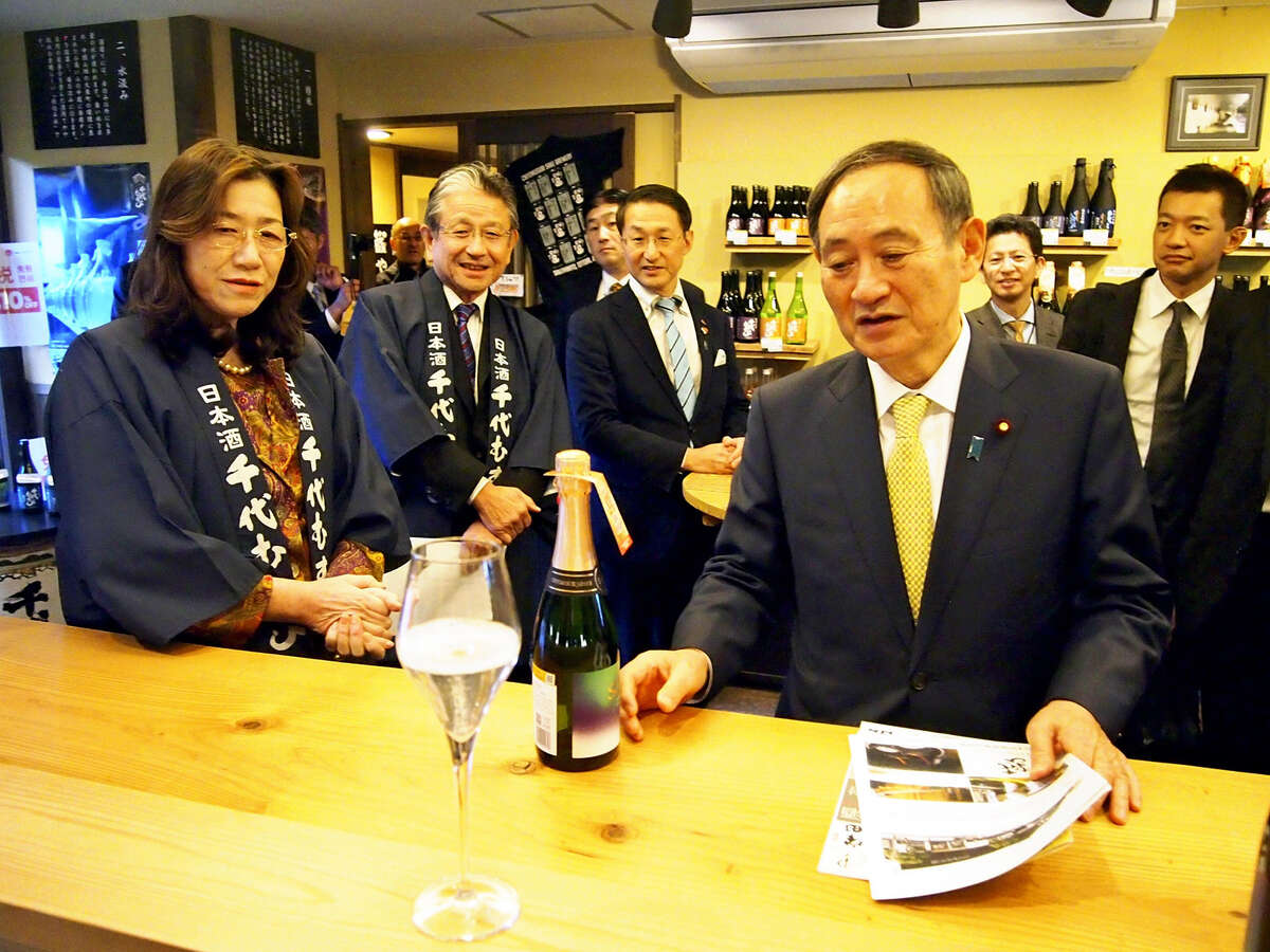 Japan's Chief Cabinet Secretary Yoshihide Suga, right, visits a sake brewery in Sakaiminato, Tottori Prefecture, on Monday.