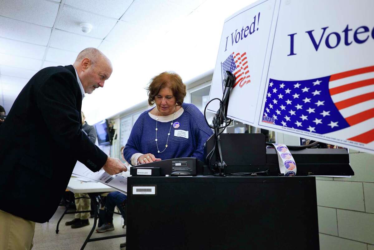 Troy Mayor Patrick Madden, left, feeds his ballot into the voting machine as election inspector Sharon Kelly looks on at School 16 on Tuesday, Nov. 5, 2019, in Troy, N.Y. (Paul Buckowski/Times Union)