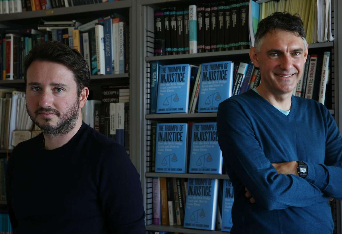 Gabriel Zucman (l to r), Professor of Economics, UC Berkeley, and Emmanuel Saez, Professor of Economics, UC Berkeley, stand for a portrait with their book “The Triumph of Injustice: How the Rich Dodge Taxes and How to Make Them Pay” displayed behind them on Monday, November 4, 2019 in Berkeley, Calif.