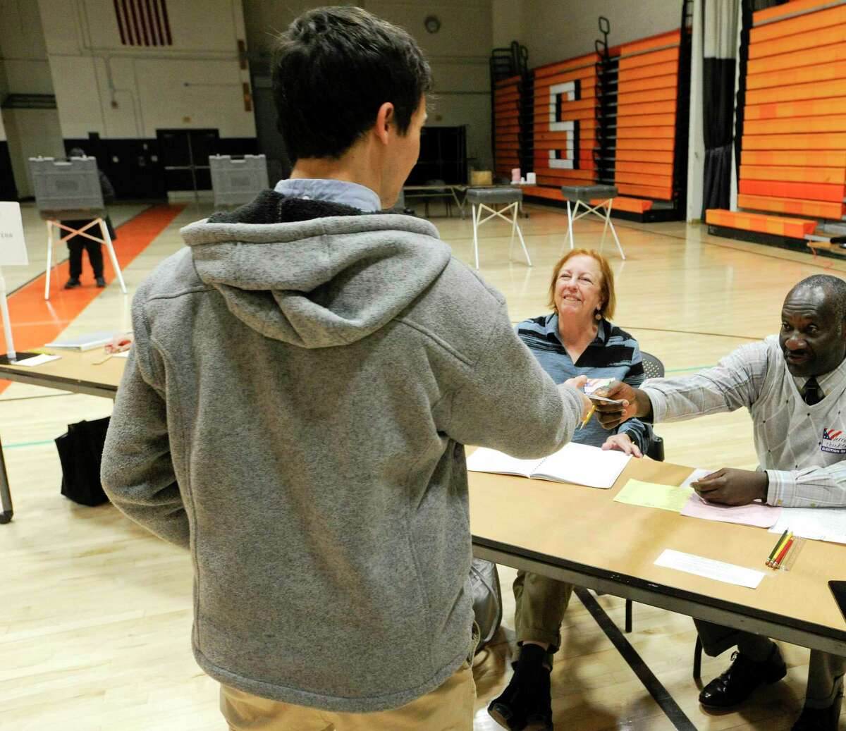 Election workers Christie Irvin and Vernond Souffrant check in a resident at District 12 polling site at Stamford High School on Nov. 5, 2019 in Stamford, Connecticut.