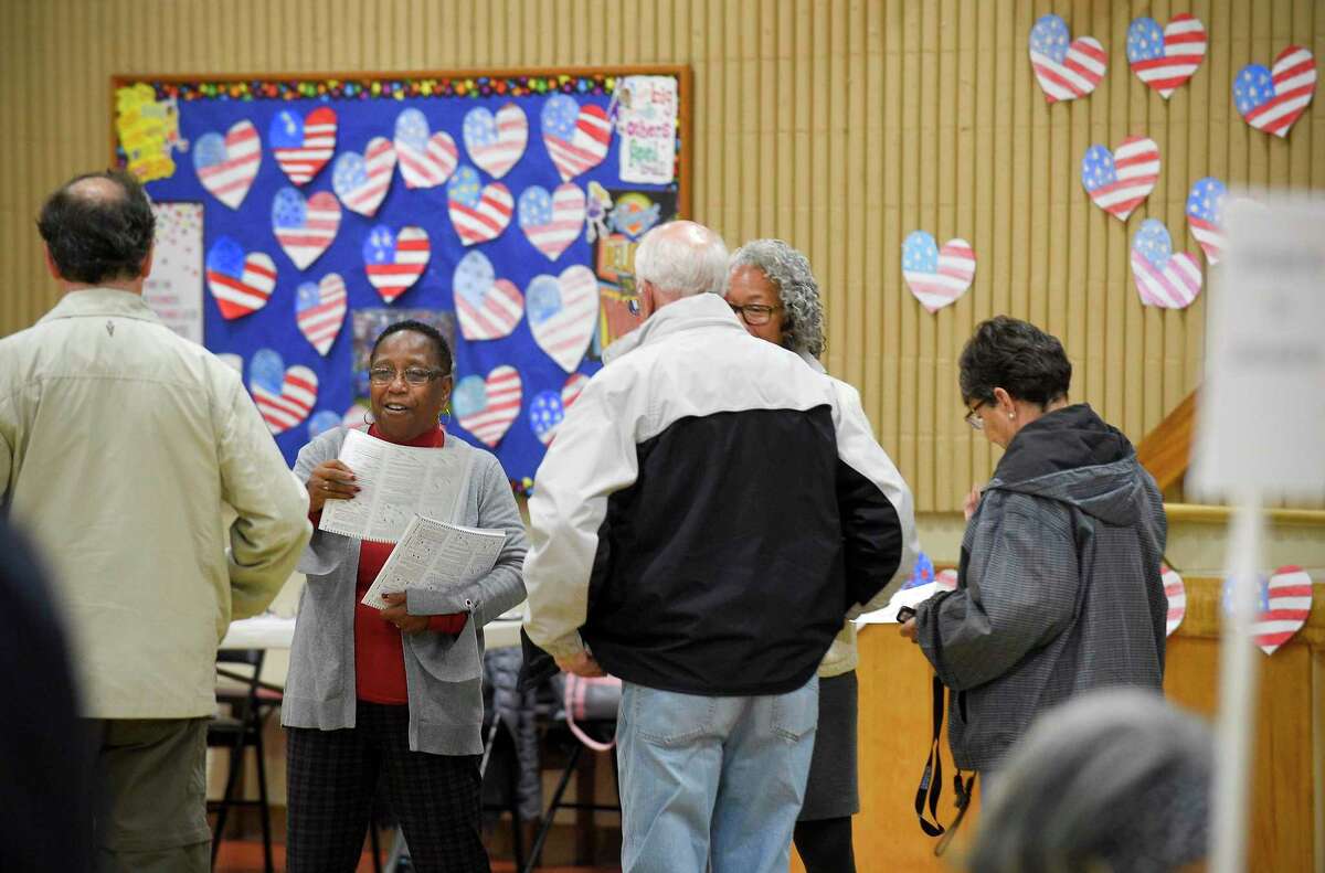Blanche Johnson, second from left, an election worker at the District 14 polling site at Stillmeadow Elementary School, hands out ballots to residents as they cast their vote on Nov. 5, 2019 in Stamford, Connecticut.