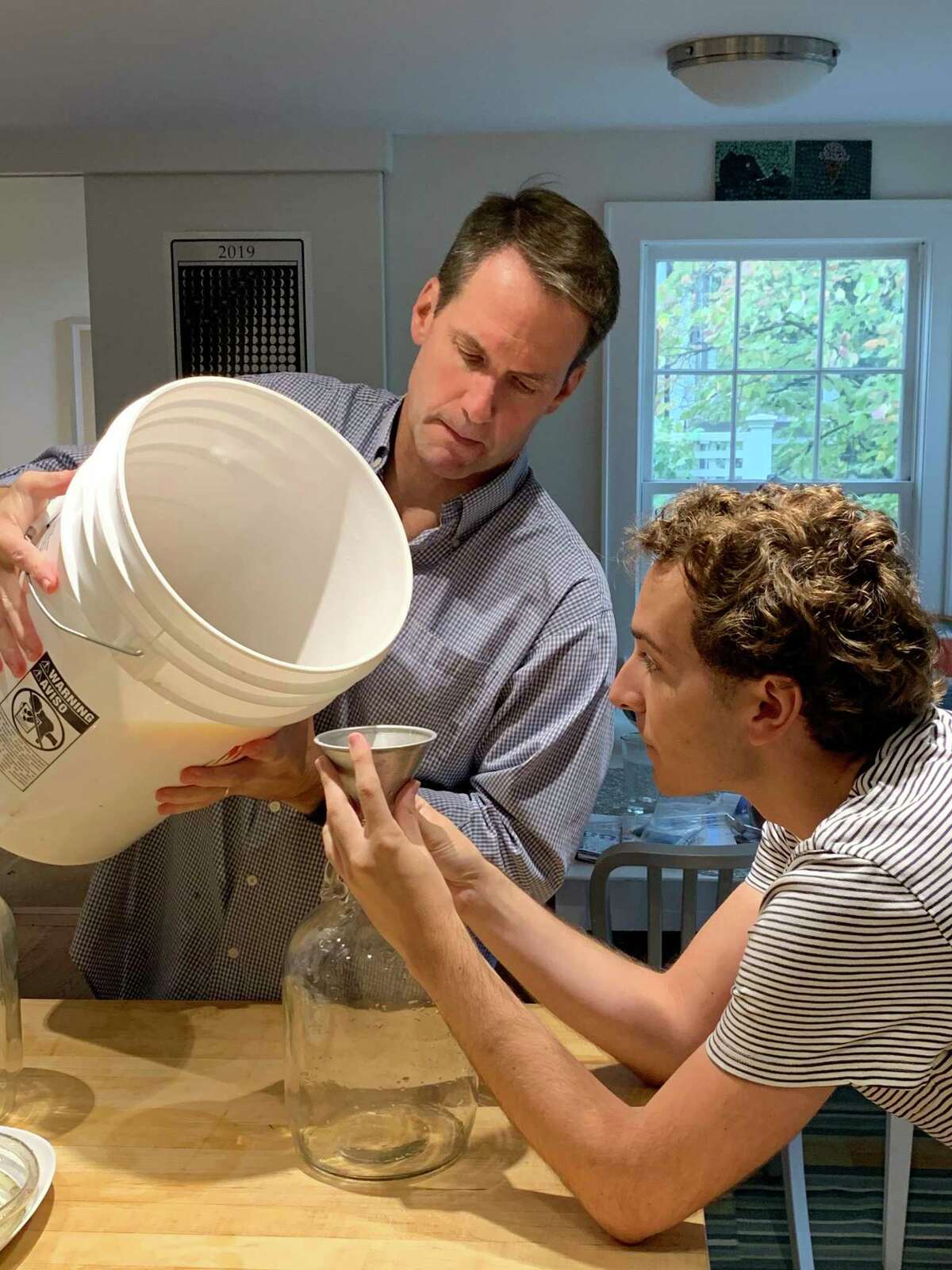 U.S. Rep. Jim Himes and Sen. Will Haskell starting a batch of cider to ferment.