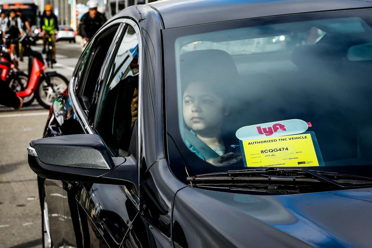 A woman looks out from a Lyft car outside the Cal Train station on Townsend Street in San Francisco, California, on Monday, May 20, 2019. Both Uber and Lyft have agreed to a 3.25%-per ride tax in an effort to avoid a tax on their gross receipts. The taxes will generate an estimated $30 million to $35 million for transportation improvements and street-safety upgrades.