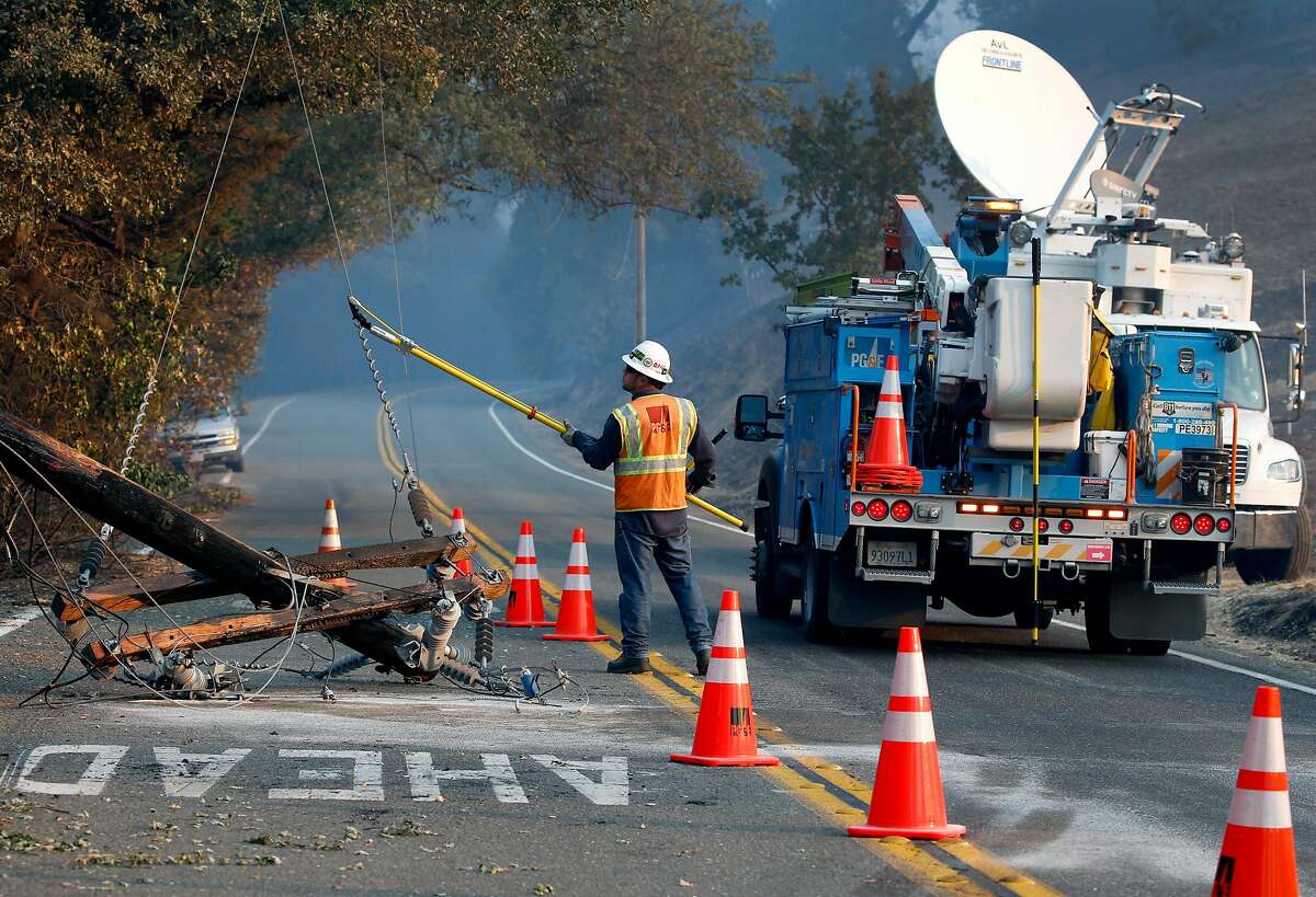 A PG&E worker severs the power line from a fallen utility pole on Geysers Road as the Kincade Fire continues to burn out of control near Geyserville, Calif. on Saturday, Oct. 26, 2019.