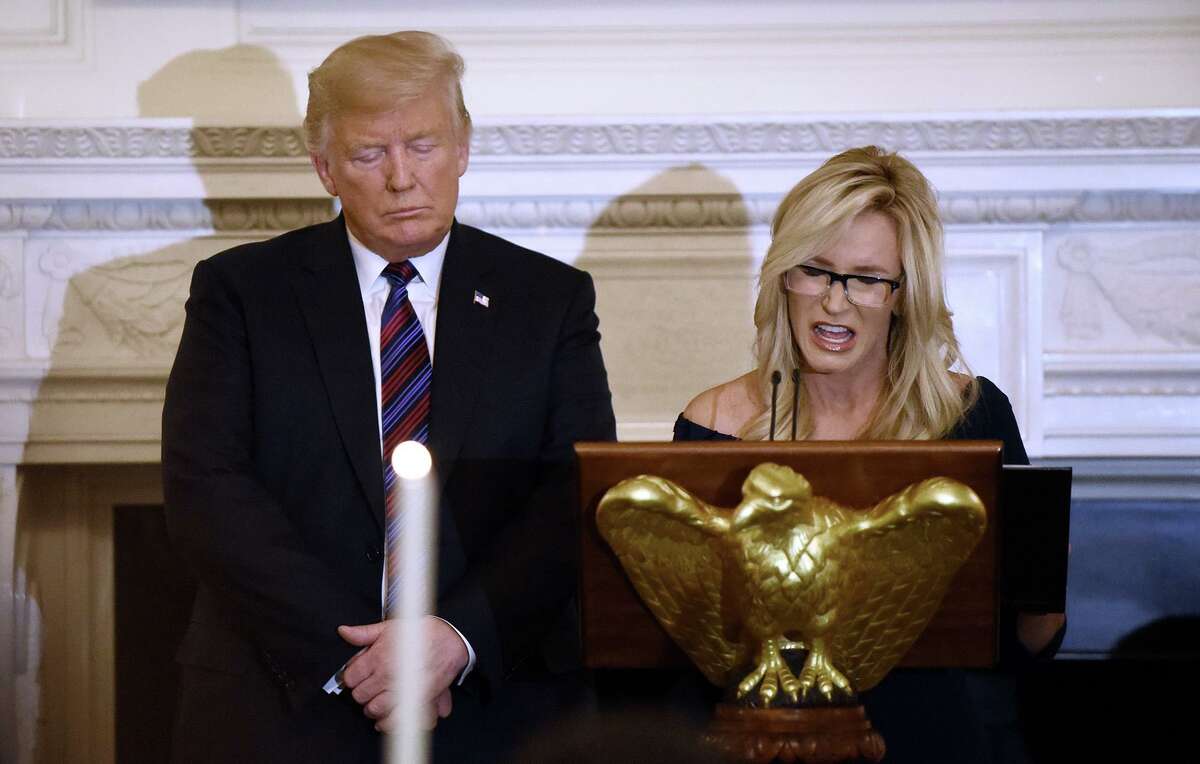 President Donald Trump listens to evangelist and pastor Paula White as she leads the prayer during a dinner for evangelical leadership in the State Dining Room of the White Houseon Aug. 27, 2018.