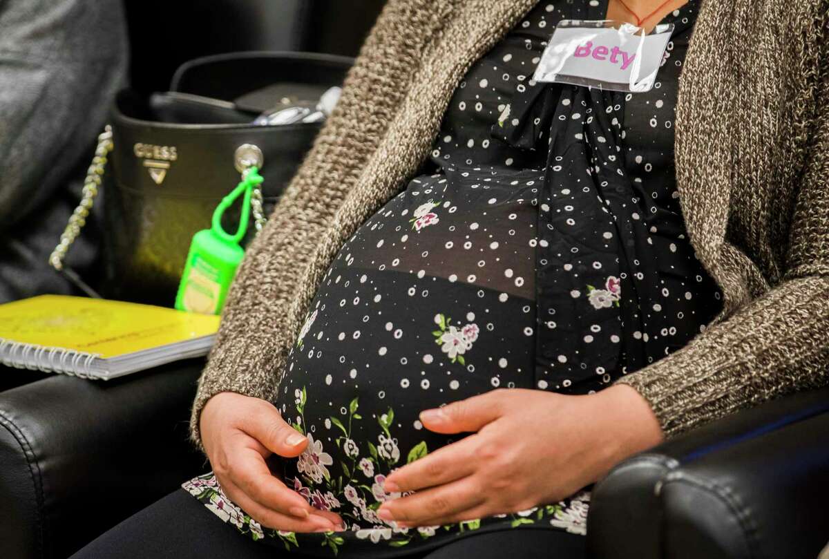 A woman rests her hands on her baby bump at a prenatal care group session at El Centro de Corazón, one of the many clinics that competed with the Heidi Group for funding.
