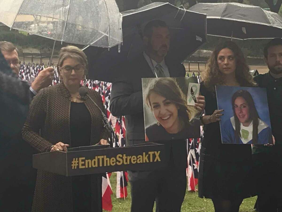 Texas Transportation Commission member Laura Ryan stands with relatives of people killed in roadway crashes outside Houston City Hall at an event Nov. 7, 2019, marking the 19th anniversary of the last day without a road fatality in Texas. Officials staked 3,647 Texas flags, one for each of the people killed on state roadways in 2018, around the Hermann Square Park fountain.