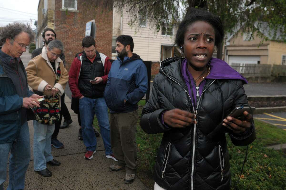 Surrounded by supporters outside the Derby courthouse, Shaundrece Beckford speaks on a cellphone with her husband, Domar Shearer, shortly before he was safely escorted to a waiting vehicle after spending most of the day sheltered in the public defender’s office to avoid being detained by Federal immigration agents in Derby Oct. 31.