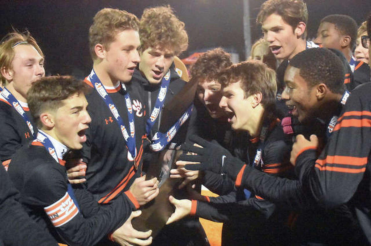 The Edwardsville boys soccer team celebrates with the Class 3A state tournament third-place trophy after defeating St. Patrick 3-2 on Saturday in Hoffman Estates.