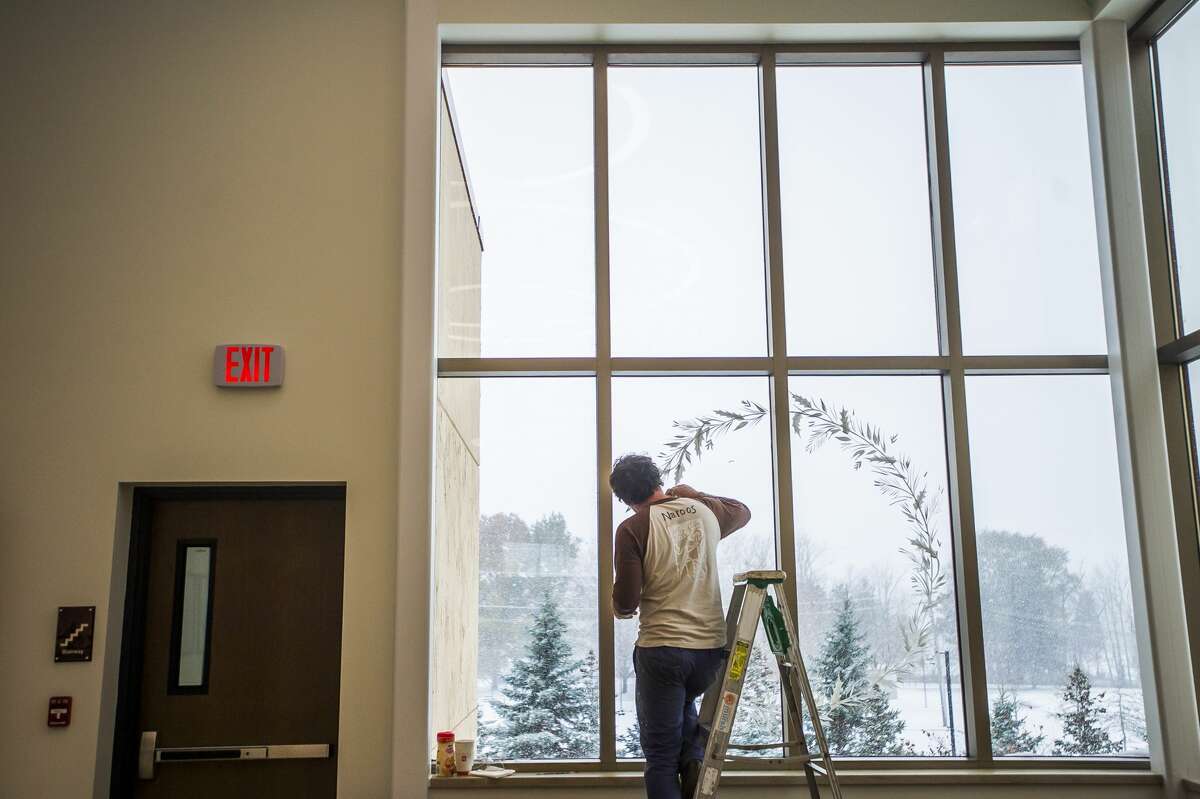 Narooz Soliman of the Brush Monkeys painting group adds a winter scene to a window at the Midland County Courthouse Monday, Nov. 11, 2019. (Katy Kildee/kkildee@mdn.net)