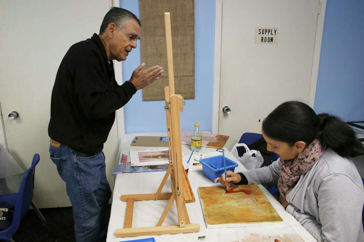 Marine veteran Juvencio Garcia (left) chats with Grace Burmudez, who served in the Army, as she works on a painting during a veterans' art class.