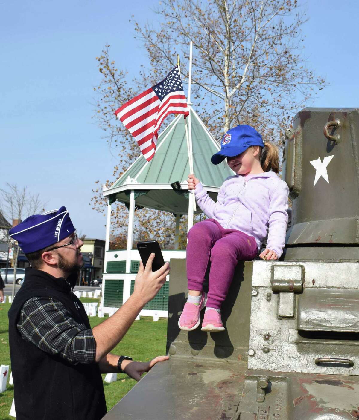 Veteran Matthew Hayes shows his daughter, Eliza, 4, the photo he took of her atop the tank on the Green before the ceremony.